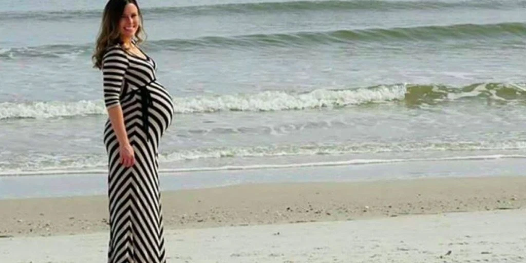 Pappa tar bilde av tungt gravid kone på stranden, men plutselig vises noe uventet i bakgrunnen